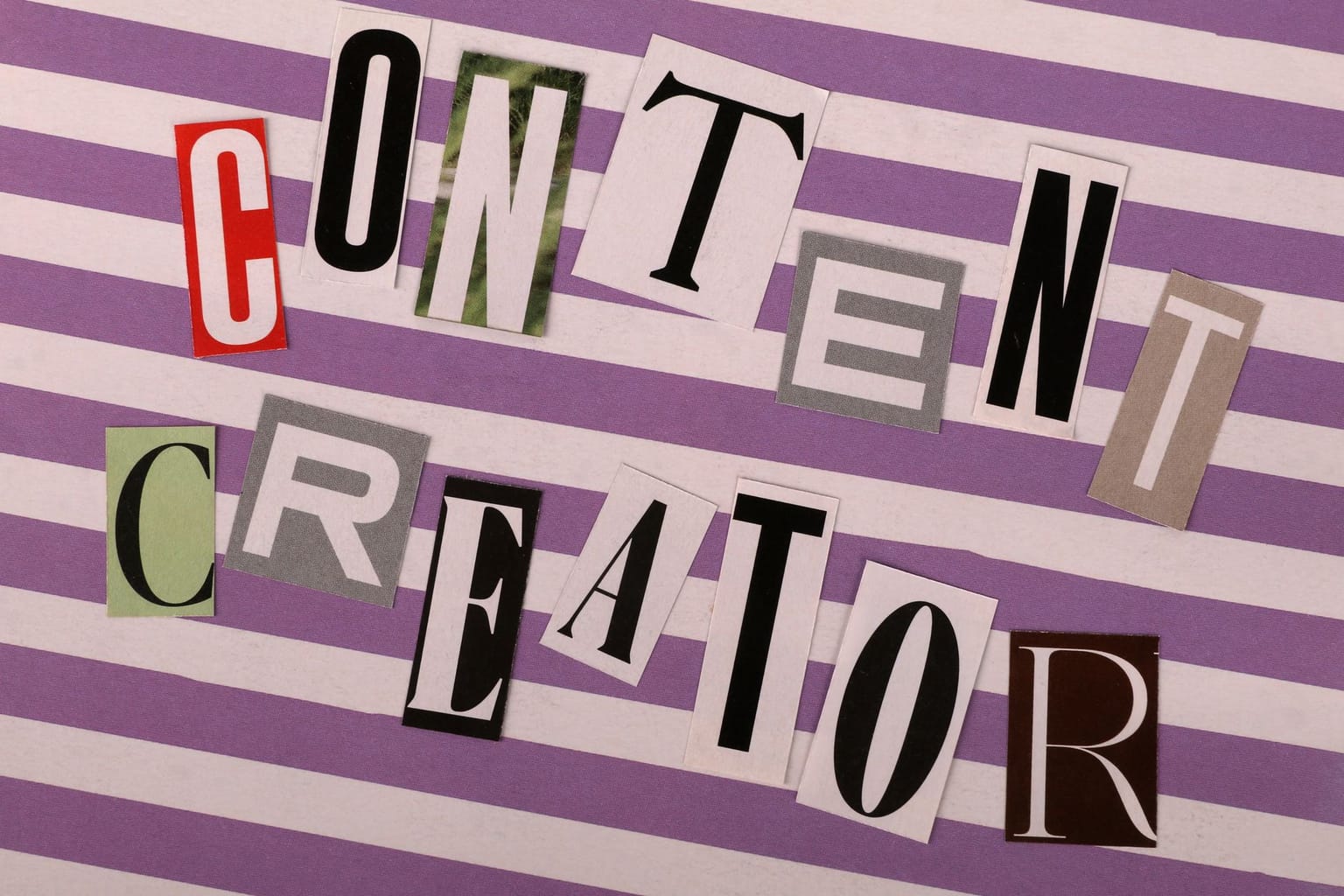 The words “Content Creator” are spelled out using cut-out magazine letters on a purple and white striped background