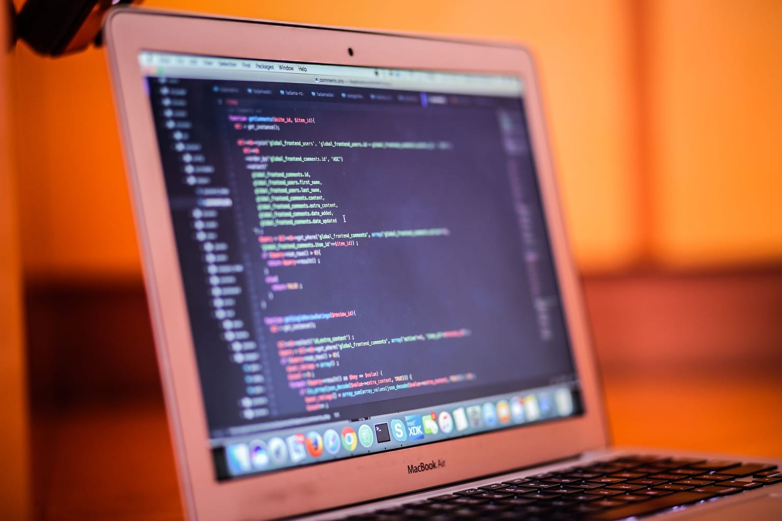 A MacBook laptop displays colorful lines of code on a text editor, evoking the spirit of open source workspace innovation