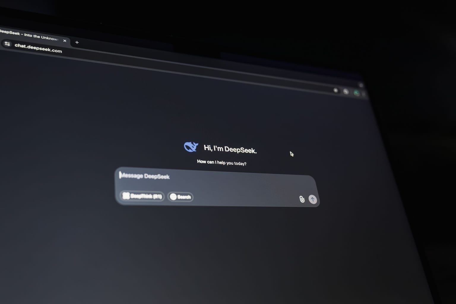 A computer screen displays an AI chatbot interface on a dark background with a conversation starter and a text input box