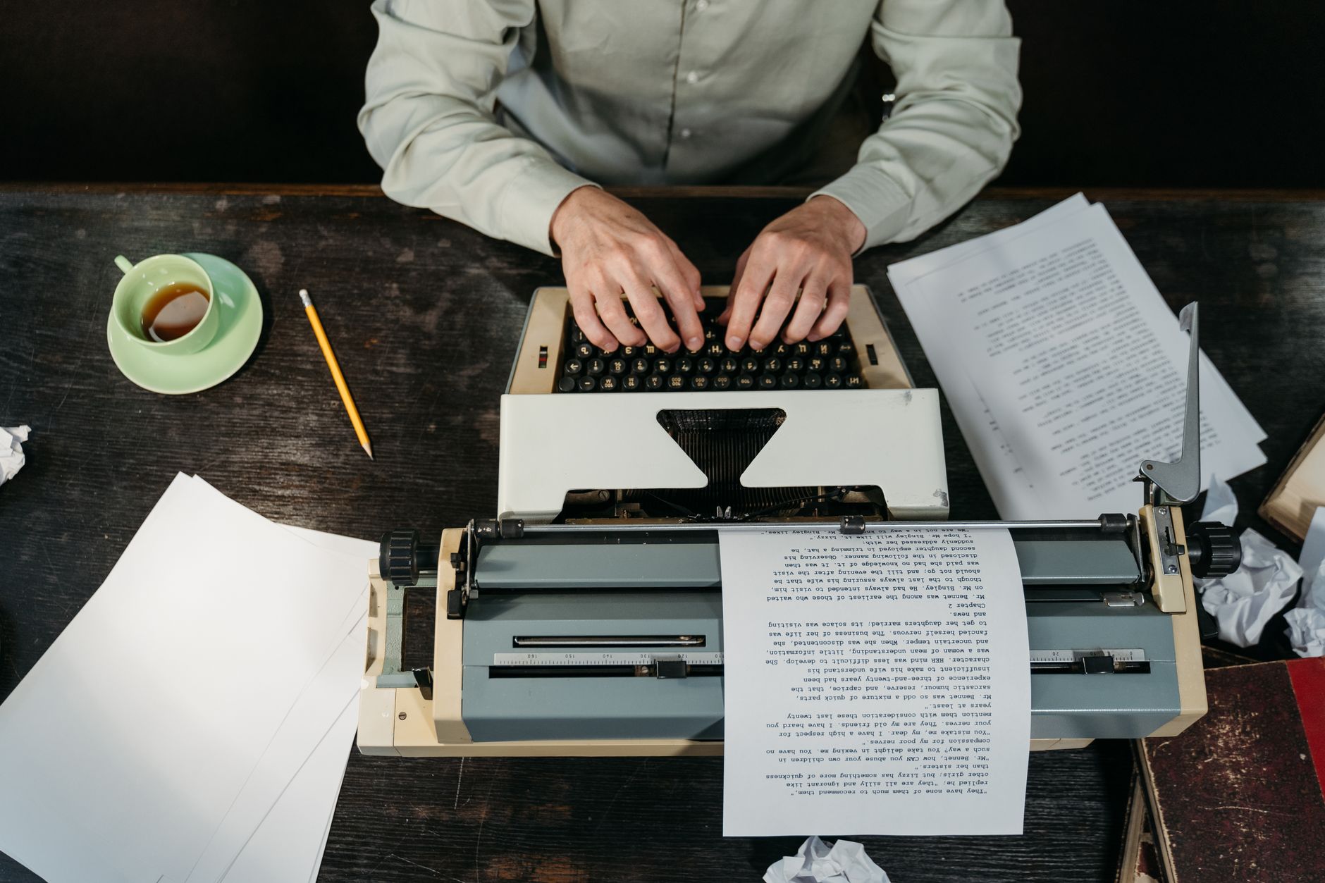 Hands typing on a typewriter beside papers and coffee, the self-publishing work Designrr buyers are doing
