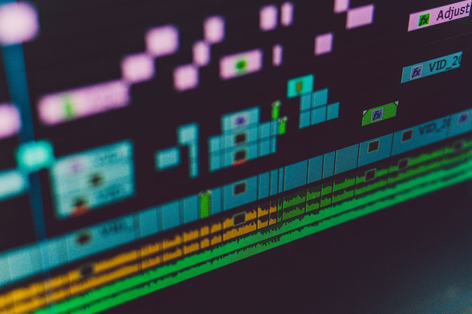 A close-up of a computer screen displaying a colorful video and audio editing timeline, showing various tracks, clips