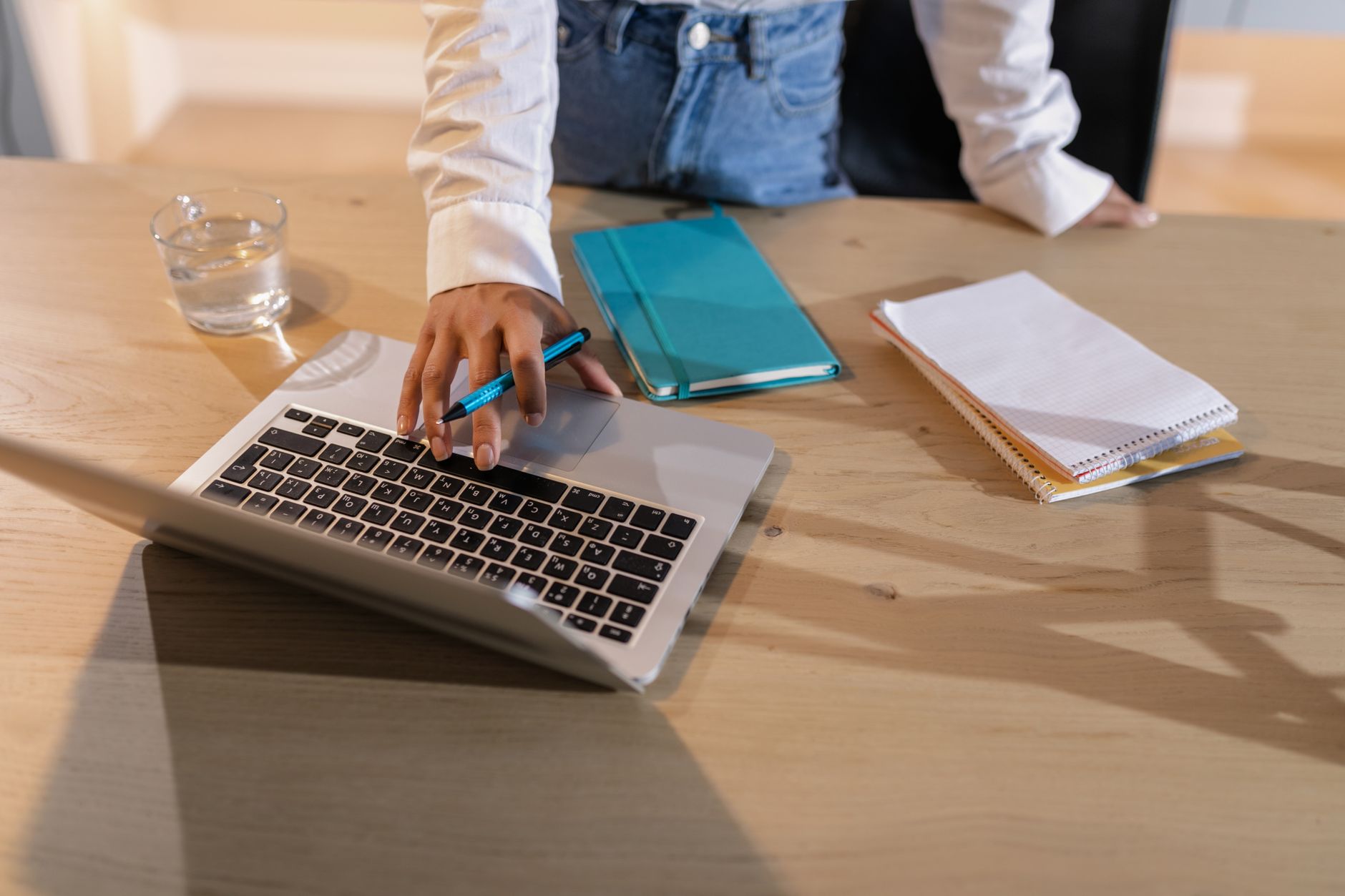 An overhead view of a person comparing options on a laptop beside notebooks, the homework a one-time storage purchase deserves