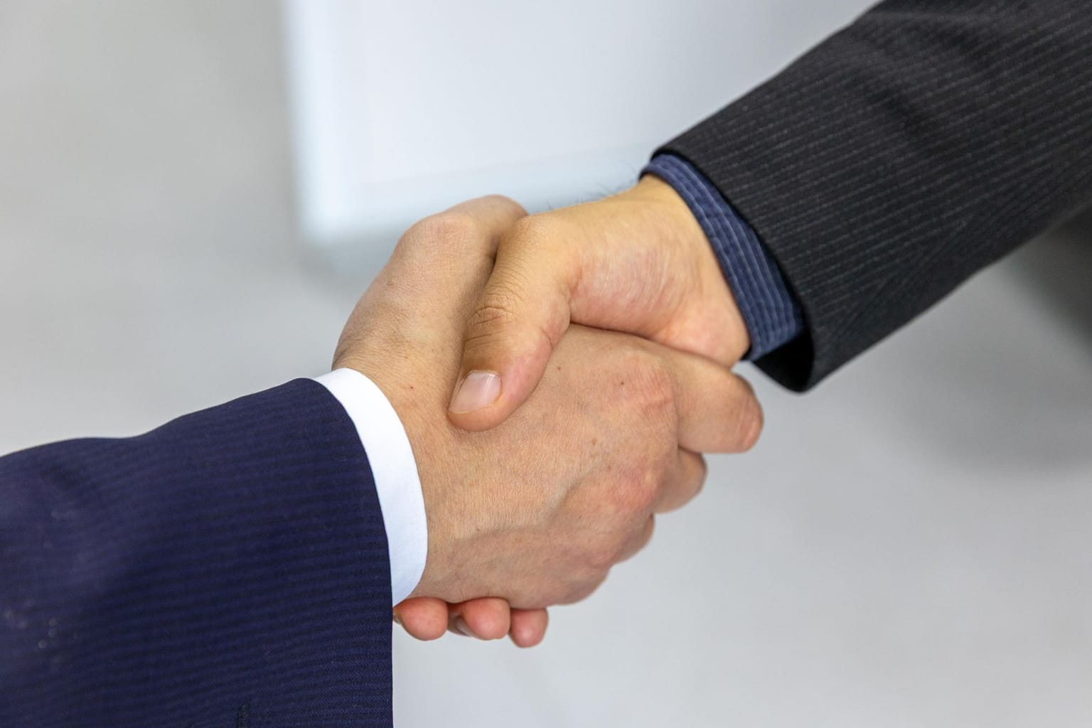 Two people wearing business suits shake hands, symbolizing agreement or partnership on a Moosend lifetime deal