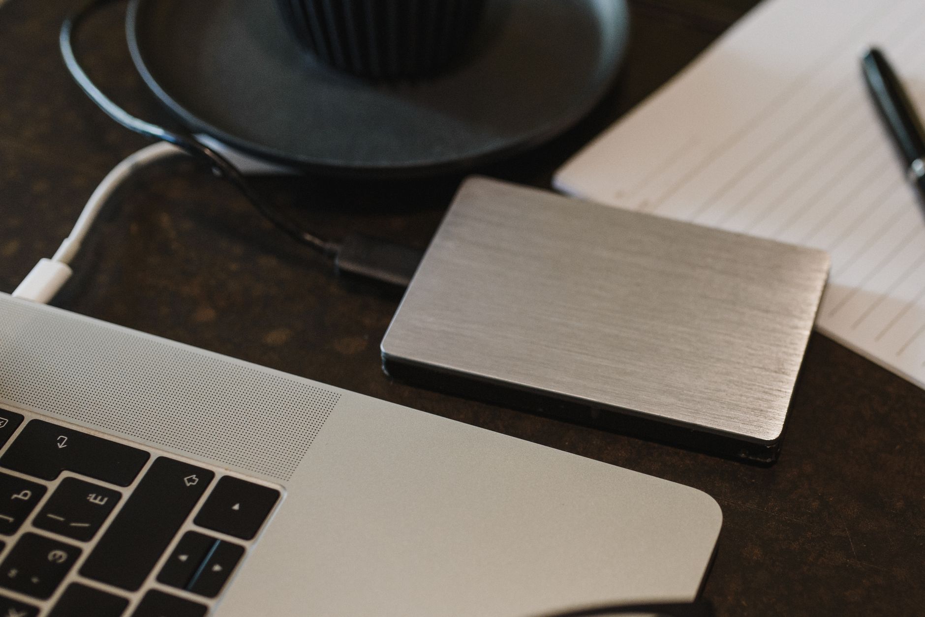 An external hard drive plugged into a laptop on a desk, the local backup a lifetime cloud plan should sit alongside