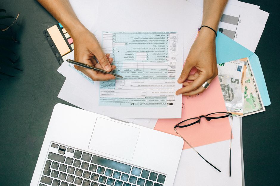 Hands filling in forms at a desk with a laptop, glasses and documents, the kind of check PitchGround lifetime deals buyers now need to do on their own