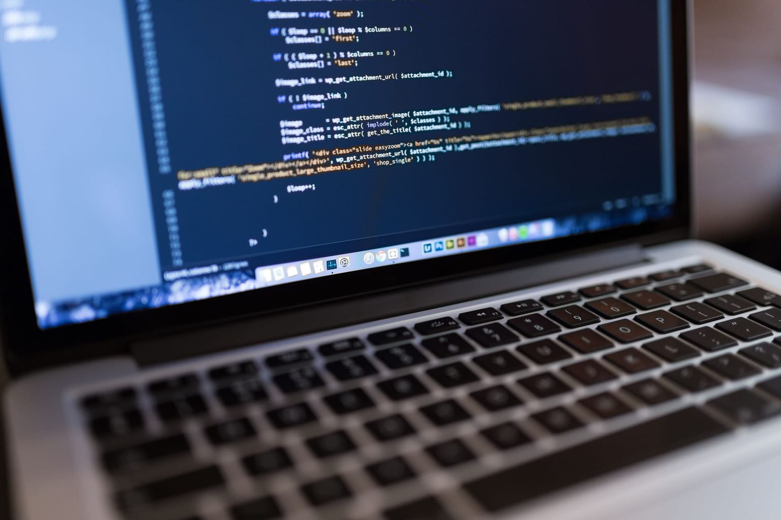 A close-up of a laptop keyboard and screen displaying lines of code in a text editor